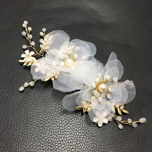 Dettaglio di un accessoire per capelli da sposa con fiori in rete 3D e filo dorato