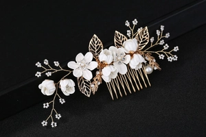 Vue détaillée du peigne à cheveux de mariée avec fleurs blanches, perles et feuilles dorées