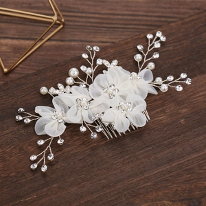 Peigne de mariée avec fleurs en tissu blanc, perles et strass sur fond en bois