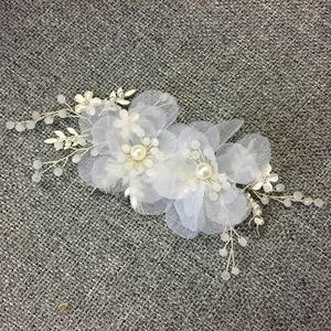 Dettaglio di pettine sposa con fiori in tulle e perle su trama grigia