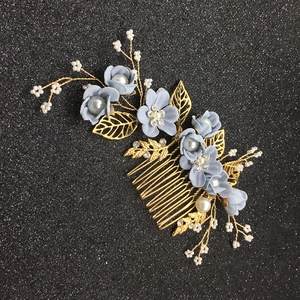 Détail d'un peigne à cheveux de mariée fait main avec fleurs bleues et feuilles dorées