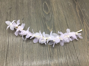 Détail de fleurs en tulle lavande et perles sur le bandeau de mariée pour coiffure de fête