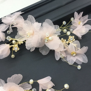 Détail de la pince à cheveux avec fleurs en mousseline rose, fil doré, perles et strass