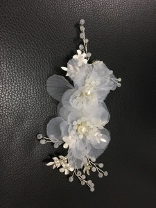Dettaglio di un copricapo da sposa con fiori di seta, perle e tralci in filo d'argento