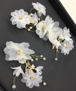 Détail de pinces à cheveux fleurs en organza blanc avec fils dorés et perles