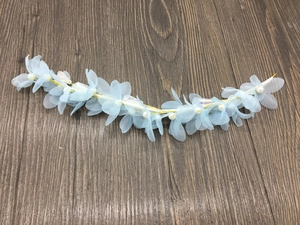 Détail de fleurs en tulle bleu clair avec perles et fil doré sur un bandeau mariée