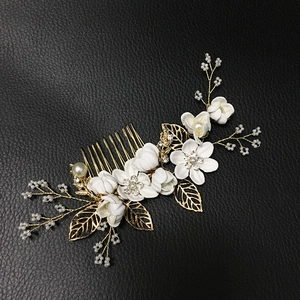 Détail d'un peigne à cheveux de mariée avec pétales blancs et feuilles dorées