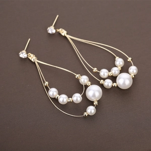 Détails de boucles d'oreilles de mariée avec perles blanches et fil doré élégant sur zircon