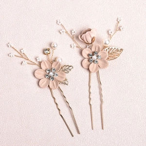 Close-up of bridal U-shaped hair pins with blue beads, pearls, and metallic leaf details