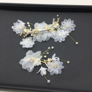 Détail d'un ensemble de pinces à cheveux de mariée avec fleurs en tissu et perles dorées