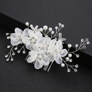 Détail d'un peigne de mariée avec fleurs en tulle blanc, perles et cristaux sur fond noir