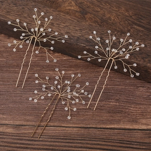 Macro shot of three gold U-shaped bridal hair pins with crystal beads on dark wood