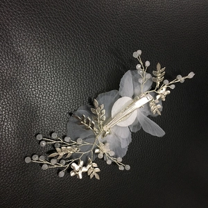 Dettaglio del fermaglio da sposa argento con foglie metalliche, perle bianche e tulle