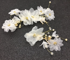 Détail de pinces à cheveux de mariée avec fleurs en mousseline blanche et perles
