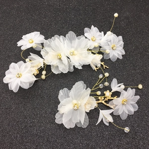 Détail d'épingles à cheveux de mariée avec fleurs en organza blanc et perles sur fil doré