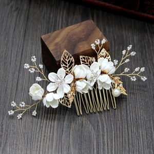 Detail of floral bridal hair comb with white silk flowers and golden leaves on wood