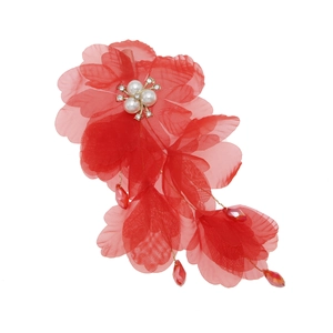 Détail de pince à cheveux fleur en tulle rouge avec perles blanches et pendentifs
