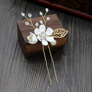 Detail of white bridal hair pin with pearls, rhinestones and golden leaf accents