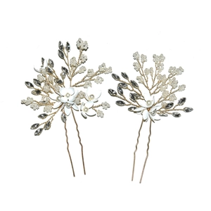 Macro detail of bridal U-shaped hair pins with white flowers, pearls, and crystals