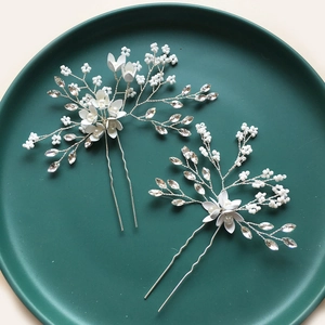 Macro detail of bridal flower hair pins with pearls and crystals on green tray