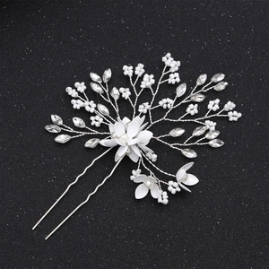Close-up of handmade bridal hair pin with white flowers, pearls and crystals