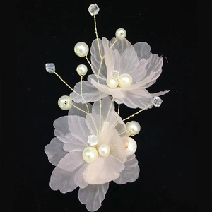Détail de fleurs en tissu et perles sur épingle à cheveux de mariée avec fils dorés