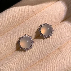 Primo piano di orecchini a bottone in calcedonio da 1,5 cm con base in argento e halo