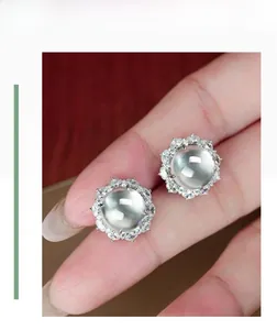 Détail macro de boucles d'oreilles en jade de quartz poli avec un halo de zircons