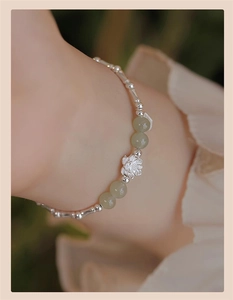 Close-up of S925 silver lotus bracelet with green jade beads on a female wrist