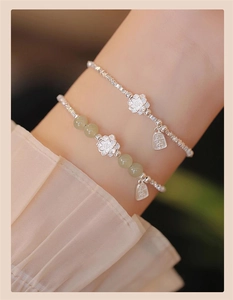 Detail view of S925 silver flower charm and Hetian jade beads on stacked bracelets