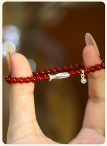 Detalle de las cuentas de ágata roja y el dije de pez koi de plata en la pulsera fina