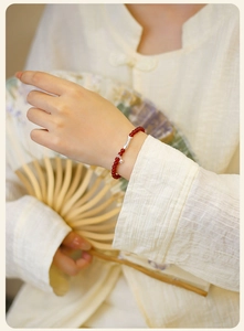 Detalle de pulsera de cuentas de ágata roja con dije de pez koi en plata fina