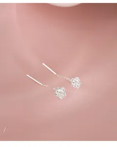 Detail of S925 sterling silver camellia flower earrings on a soft pink silk background