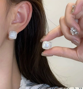 Detail view of square hoop earrings featuring micro-pave crystals and smooth pearl inlay