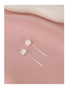 Detail of silver camellia earrings with rose-style relief and fine chain on pink silk