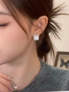 Close-up of minimalist square pavé diamond earrings worn by a model in a cozy setting