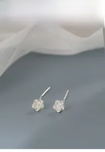 Close-up of S925 sterling silver camellia flower earrings on a textured grey background