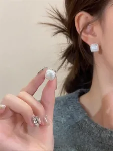 Detail of square pearl earrings with diamond accents worn on a woman's earlobe