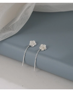 Detailed close-up of S925 sterling silver camellia flower earrings on a blue stand