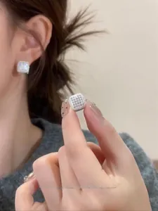 Close-up of square pavé-set diamond hoop earrings shown on a model for a chic look