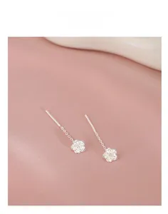 Detail view of silver camellia flower earrings on elegant pink silk background