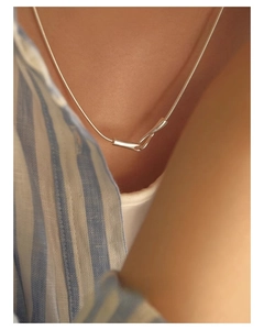Detail of minimalist sterling silver twisted knot pendant on fine snake bone chain
