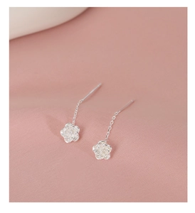 Close-up of S925 sterling silver camellia flower drop earrings on pink silk fabric