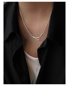 Close-up of minimalist silver snake chain necklace with an S-shaped clasp on a model