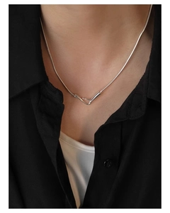 Close-up of minimalist silver snake chain necklace with intertwined lock pendant on model