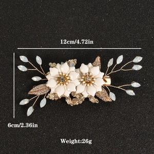 Elegant bridal hair clip with white flowers, crystals, and gold leaves on black background