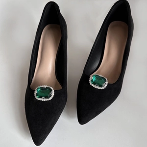 Dettaglio della fibbia in cristallo verde smeraldo su décolleté in camoscio nero