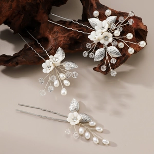 Three-piece bridal hair pin set with white ceramic flowers, metal leaves and pearls