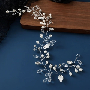 Handmade bridal headband with white pearls and silver leaves on a dark blue surface