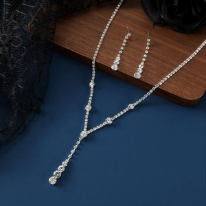 Sparkling crystal bridal jewelry set with silver necklace and drop earrings on dark decor